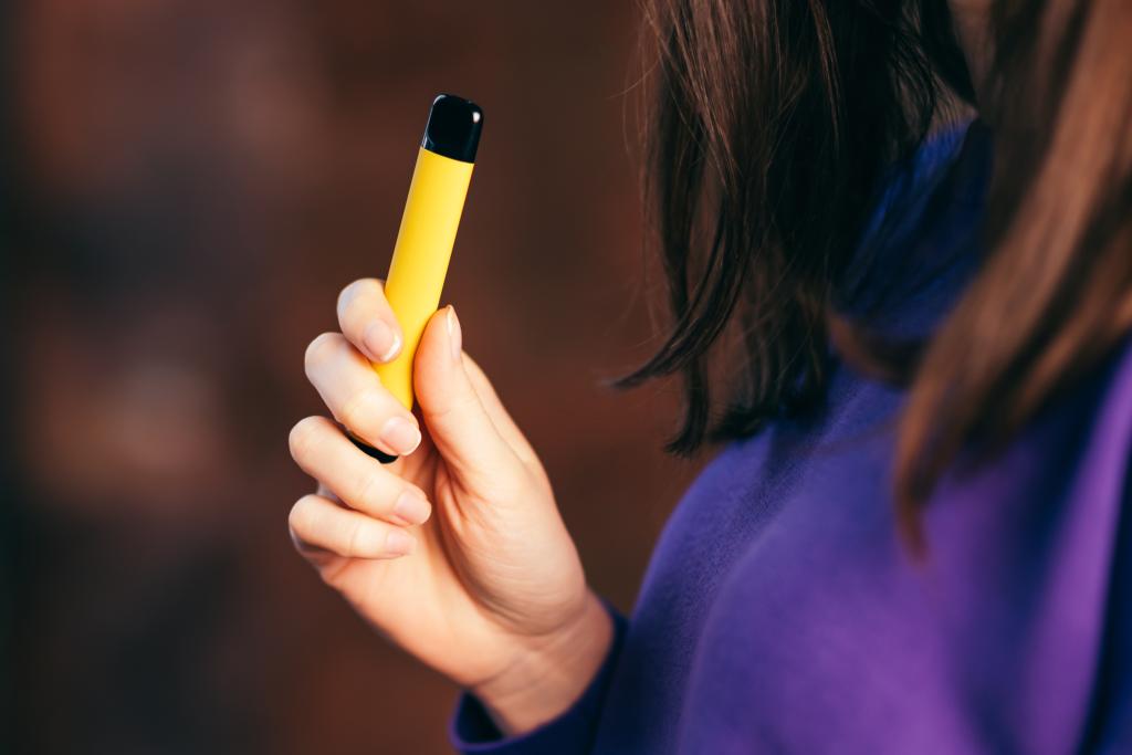 A woman smokes a vape. 