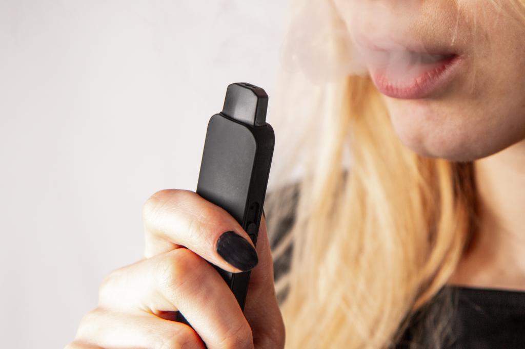 Close up of a blonde girl vaping an e-cigarette
