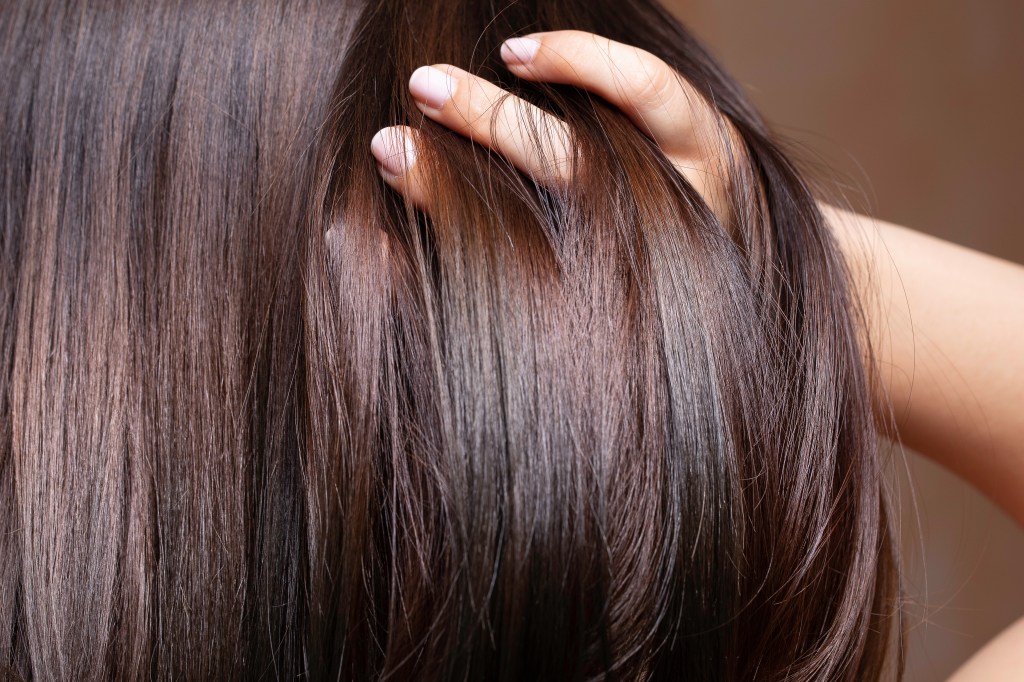 Closeup of a beautiful brunette woman stroking her glossy straightened brown hair