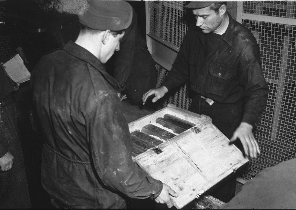 Workers inspecting gold bars confiscated from Jewish people by the Nazis, discovered in Heilbronn Salt Mines, Germany, on May 3, 1945