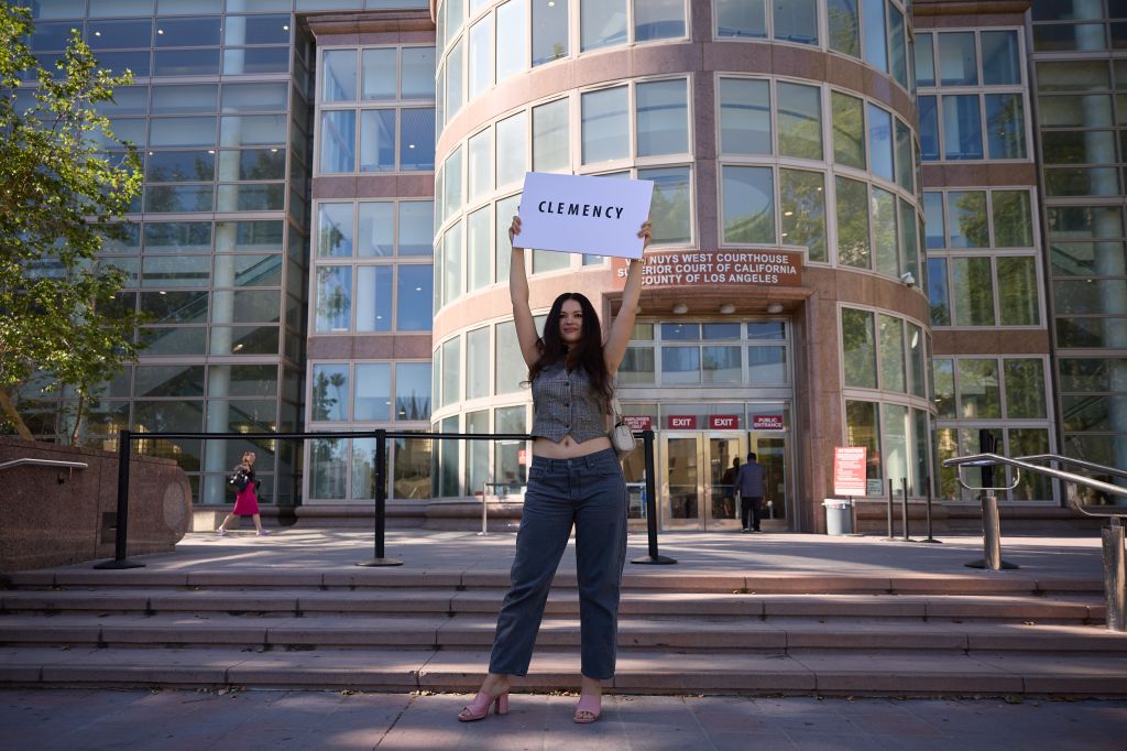 A woman holding a 'clemency' poster