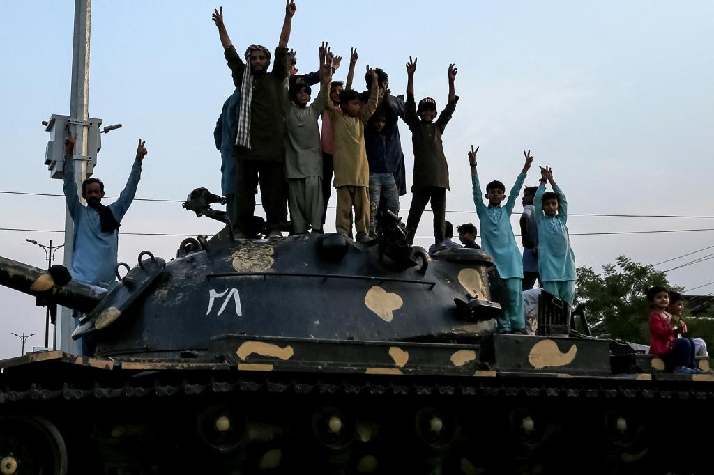 Pakistani individuals standing atop a tank, flashing victory signs in celebration of the ceasefire between Pakistan and India on May 10, 2025 in Multan.