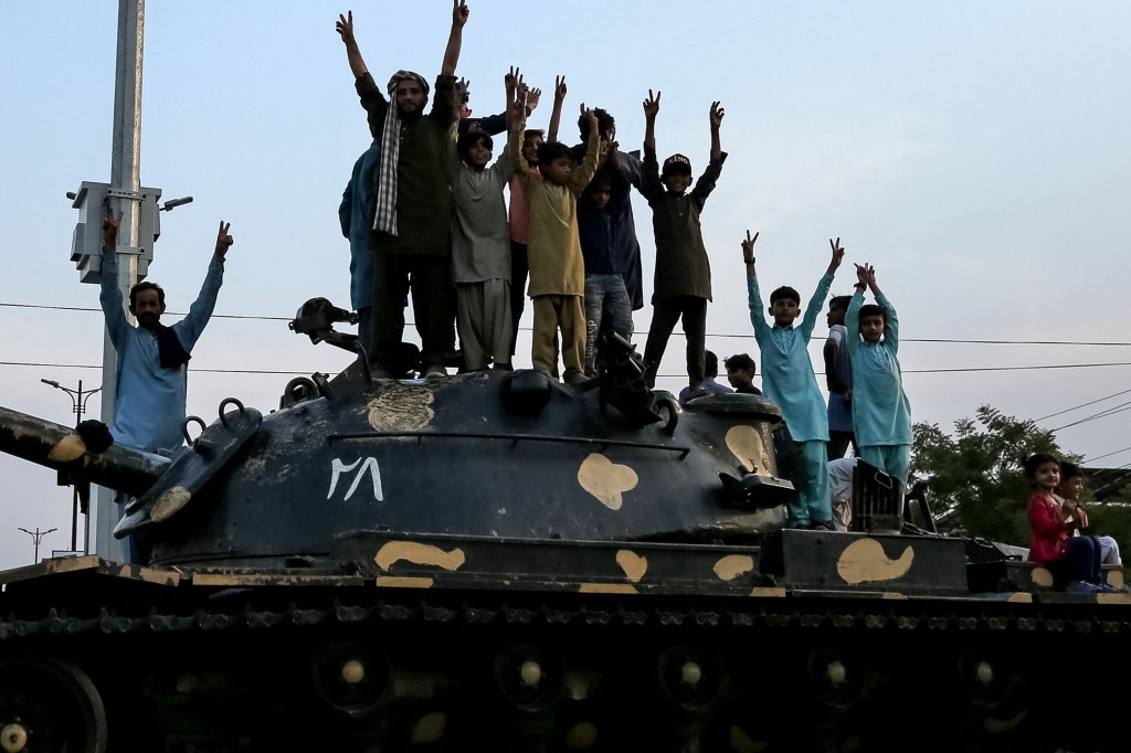 Pakistani individuals standing atop a tank, flashing victory signs in celebration of the ceasefire between Pakistan and India on May 10, 2025 in Multan.