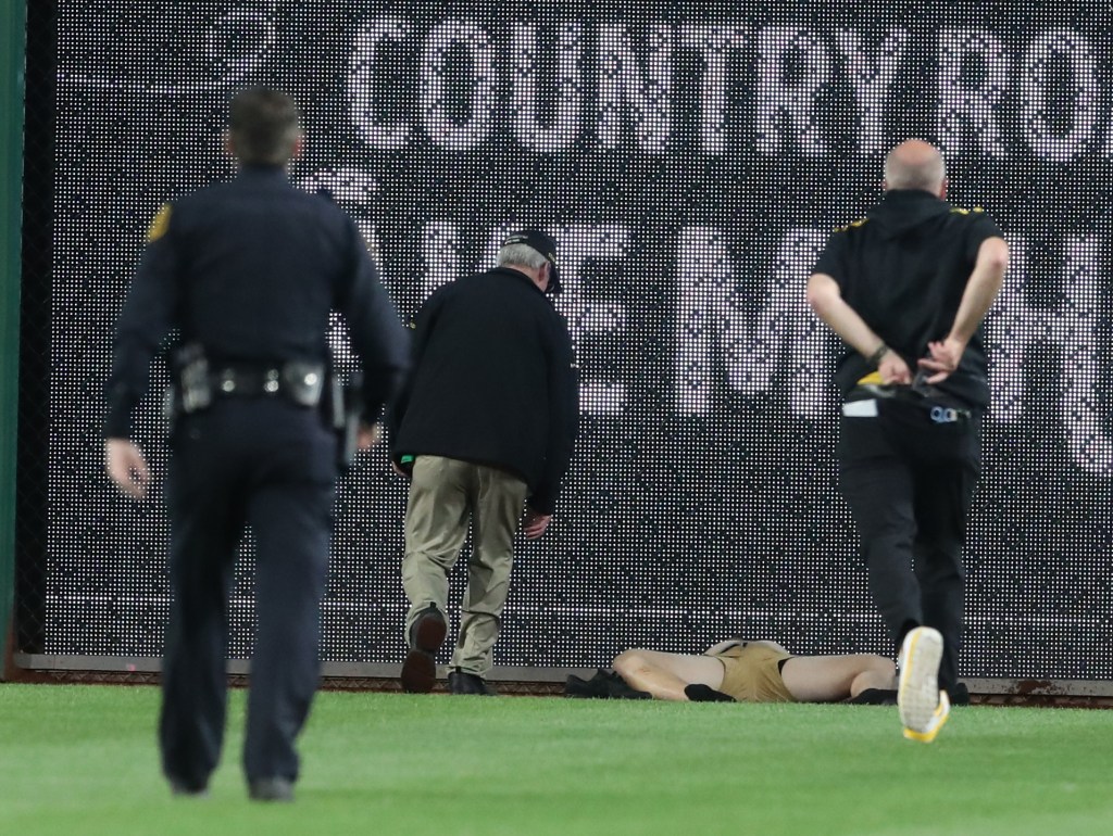 Stadium security and Pittsburgh Pirates medical personnel rush to assist a fan who fell from the stands to the field as the Pirates batted against the Chicago Cubs during the seventh inning at PNC Park. 