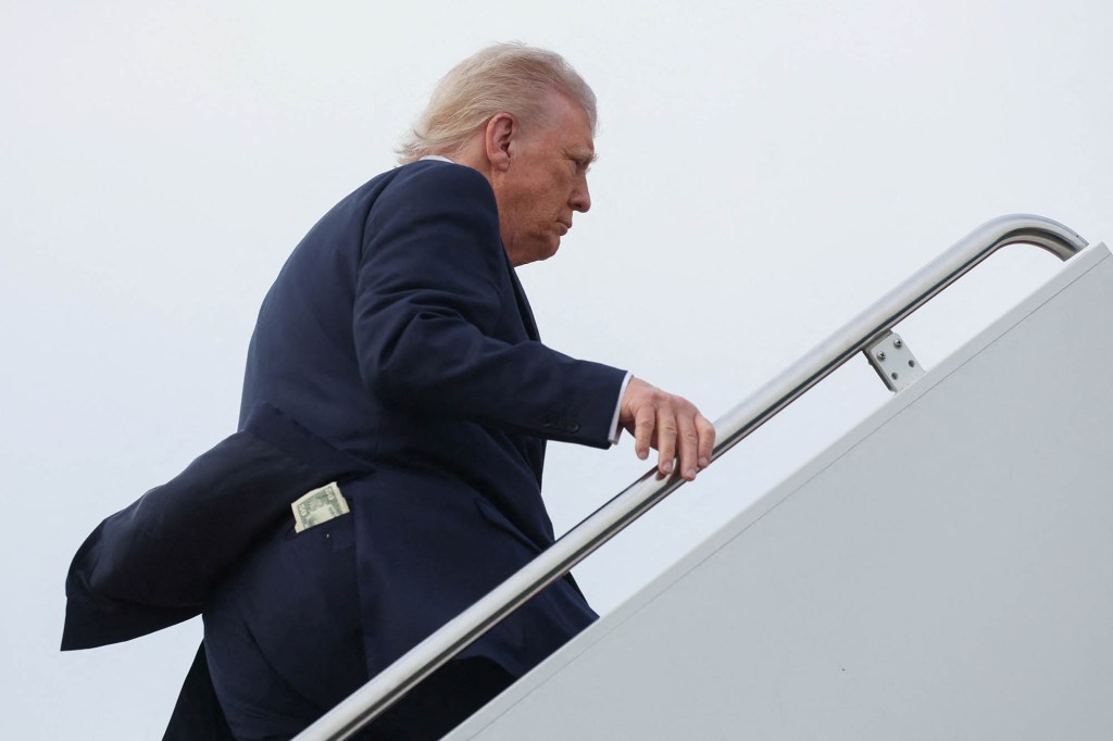 Cash including a $50 bill sticks out of his back pocket as President Donald Trump boards Air Force One bound for Alabama, at Joint Base Andrews in Maryland, U.S., May 1, 2025.