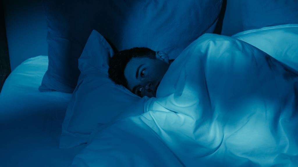 A new study finds that just three nights of sleep deprivation can increase the risk of heart disease — even in young and healthy adults. Here, a man struggles to sleep in his bed.