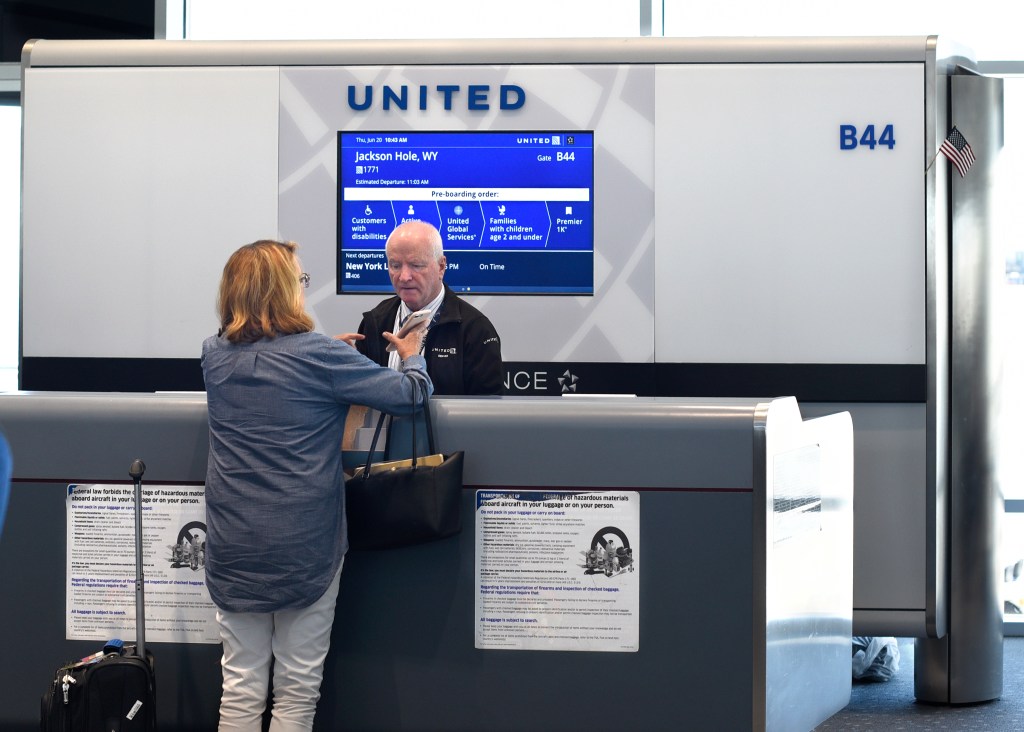 United Airlines gate agent assisting a passenger at a boarding gate in Denver International Airport