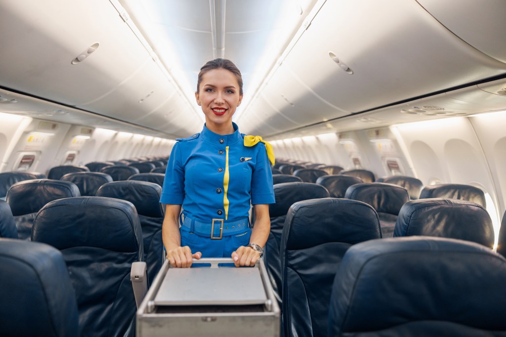 A flight attendant pushing a food and drink cart. 