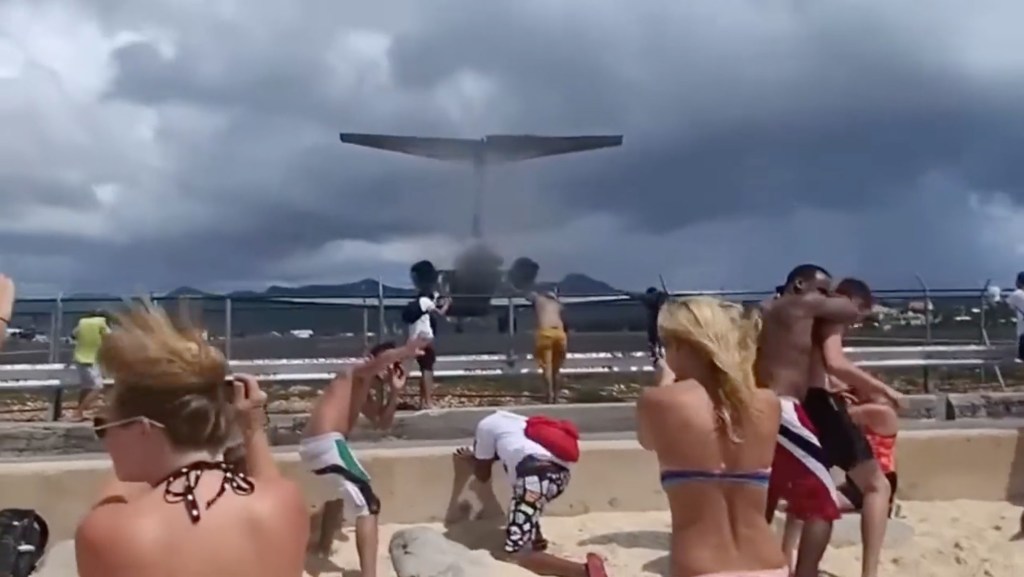 Dozens of tourists at Maho Beach in Sint Maarten, being blown away by the jet blast of an MD80 Series aircraft taking off