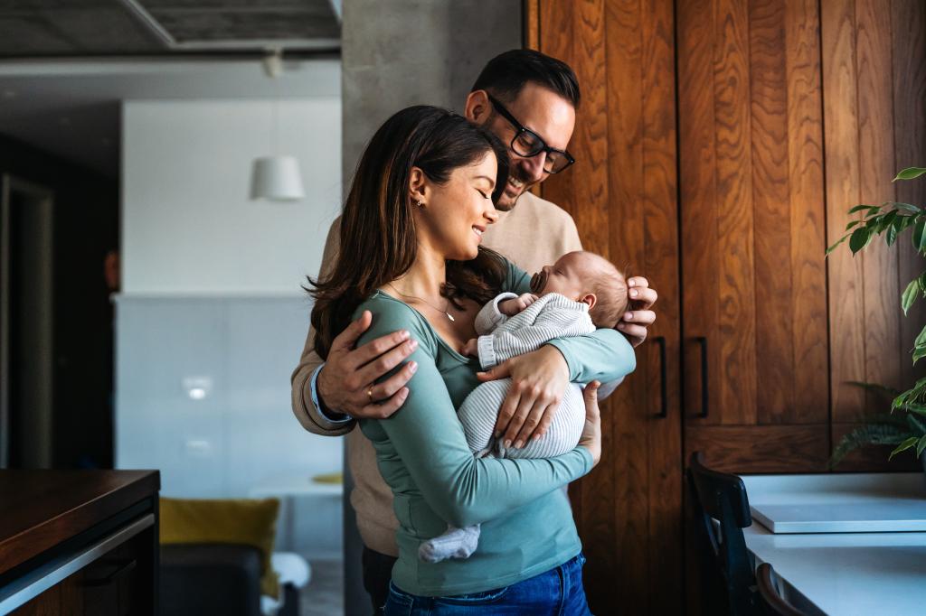 Happy young mother, father with new born baby at home.
