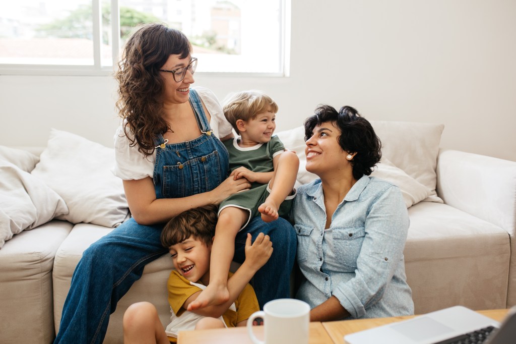 Happy lesbian couple playing with their children at home. 