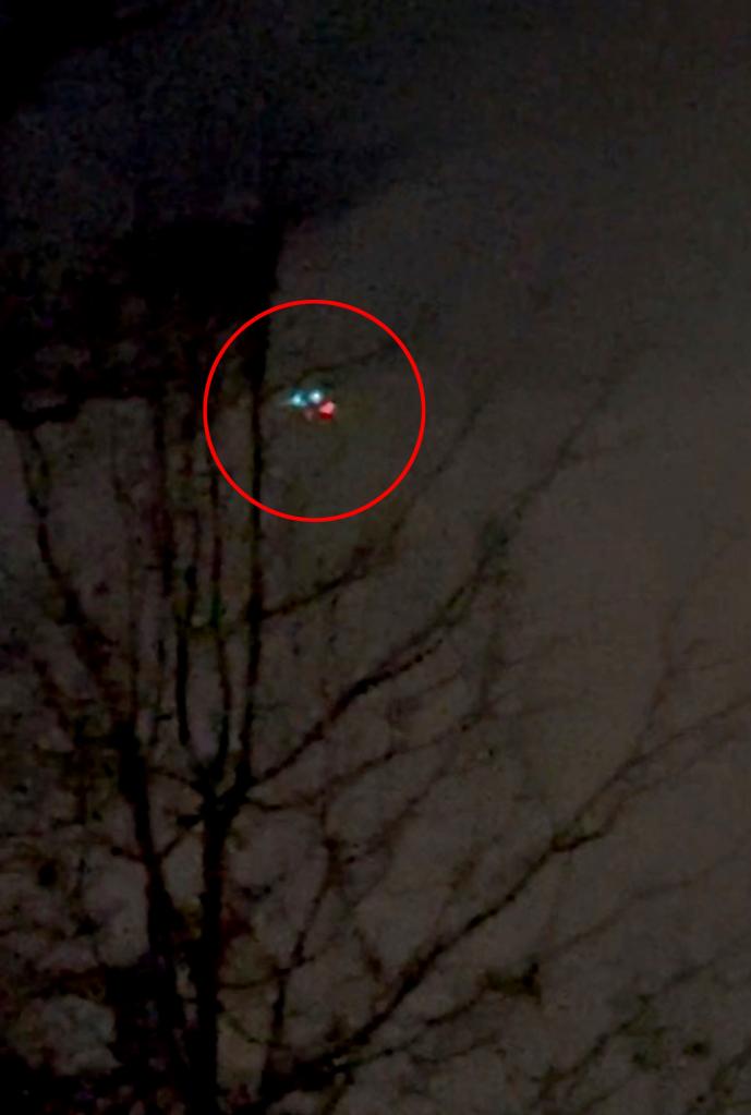 an image showing three lights close together in the night sky with a tree in the foreground