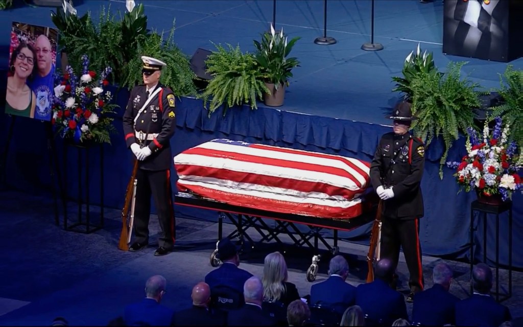 Law enforcement officers standing beside the casket of Hamilton County Special Deputy Larry Ray Henderson Jr. at a memorial service in the Cintas Center, Cincinnati, Ohio.
