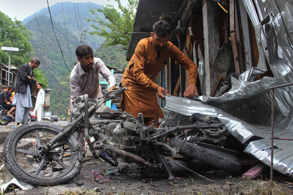 Local residents remove a burnt motorbike from near their shops damaged by Indian shelling, at the main bazaar, a day after the ceasefire between India and Pakistan was announced, near Jura, on the Line of Control, in Neelum Valley, a district of Pakistan's administered Kashmir, Sunday, May 11, 2025