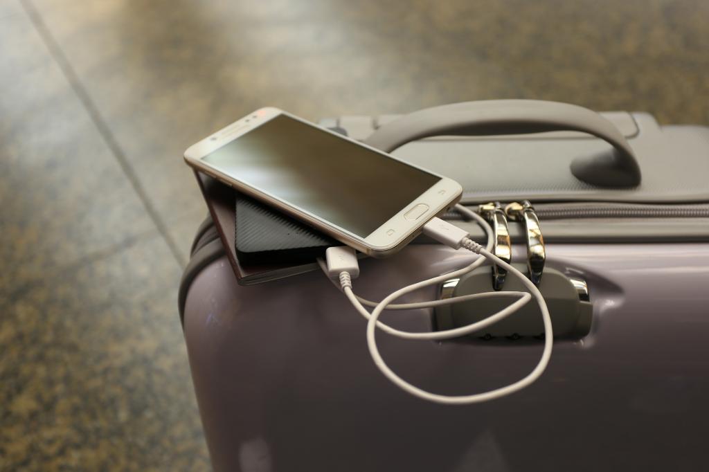 Power bank charging a smartphone placed on a travel bag in an international airport