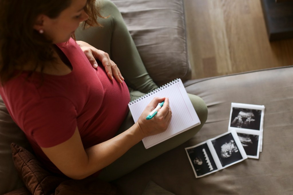 woman thinking of baby names pregnant with ultrasound pictures