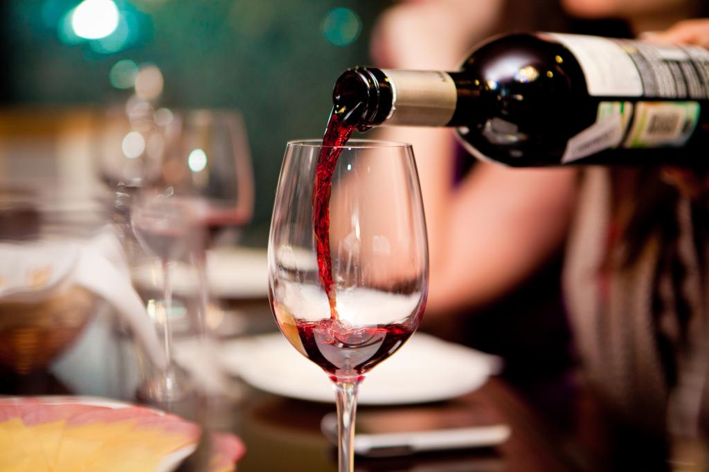 A person pours a glass of red wine. 