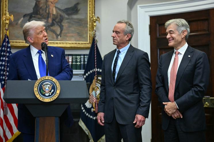 US President Donald Trump delivering a speech on prescription drug prices, with Health Secretary Robert Kennedy Jr. and Mehmet Oz attentively listening