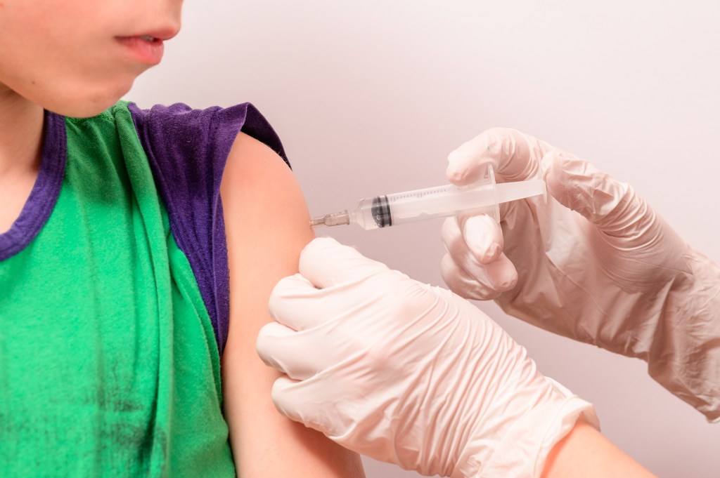 Child receiving a vaccine in the hand from a laboratory assistant to develop disease immunity