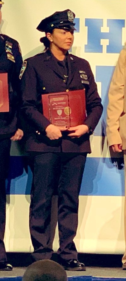 NYPD officer Nicole F. Aiello in uniform holding a red folder with gold letters. Aiello has been a cop on Staten Island for years.