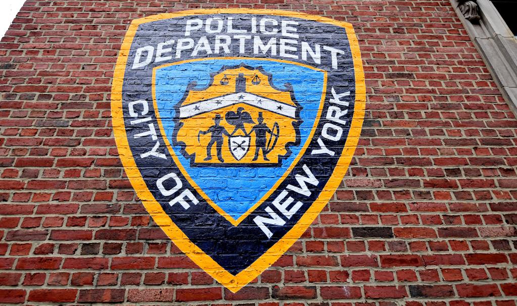 NYPD emblem painted on a brick wall.