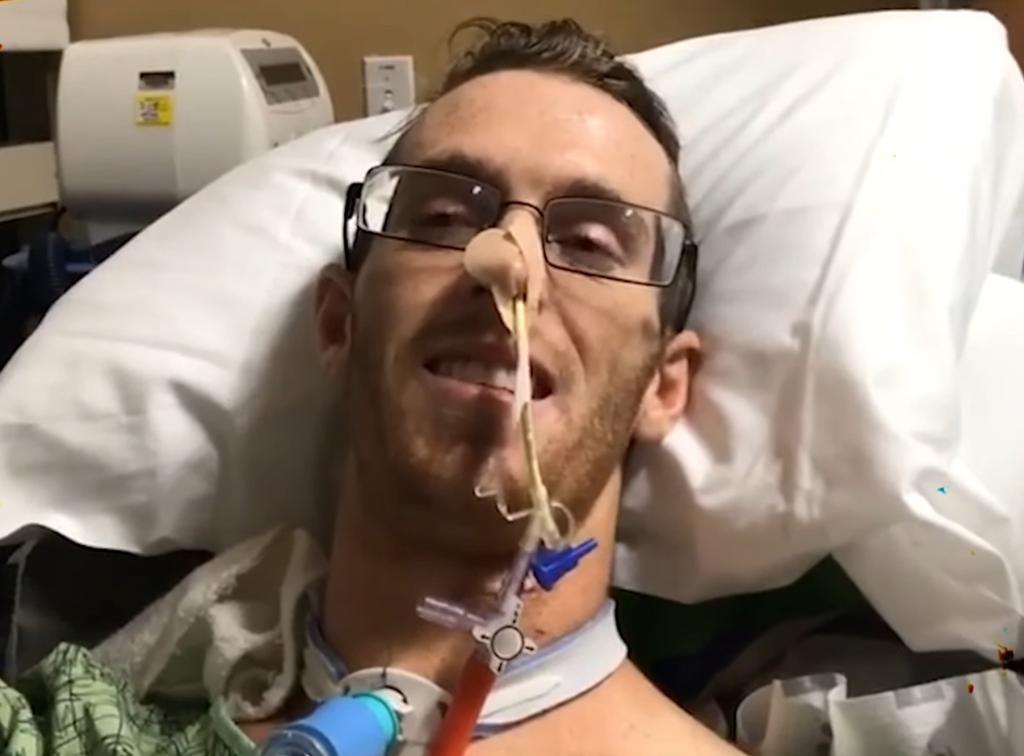 Man in hospital bed with neck brace and nasal cannula.