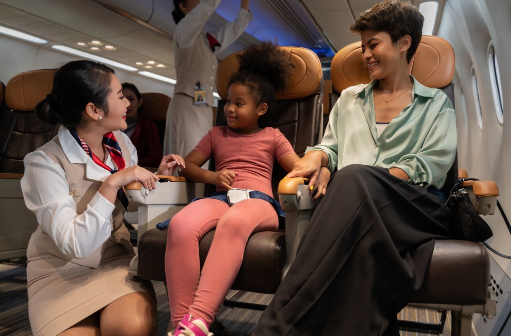Flight attendant attending to mom with little girl. 