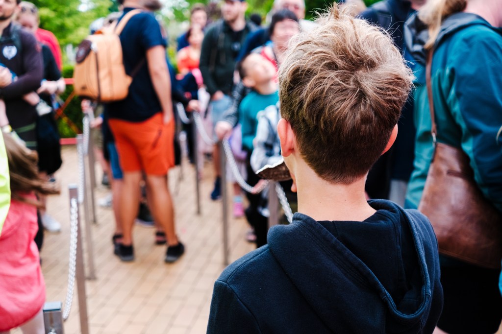 Boy waiting in line, seen from behind.