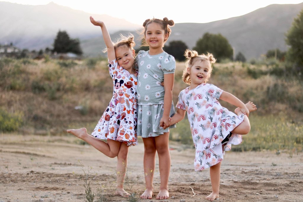 Three young sisters, Evelyn, Paityn, and Olivia Decker, standing outdoors.