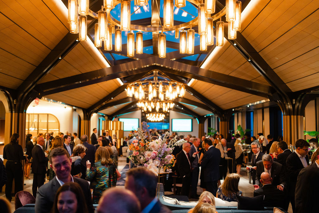 Interior of a large room with many people at a social gathering.