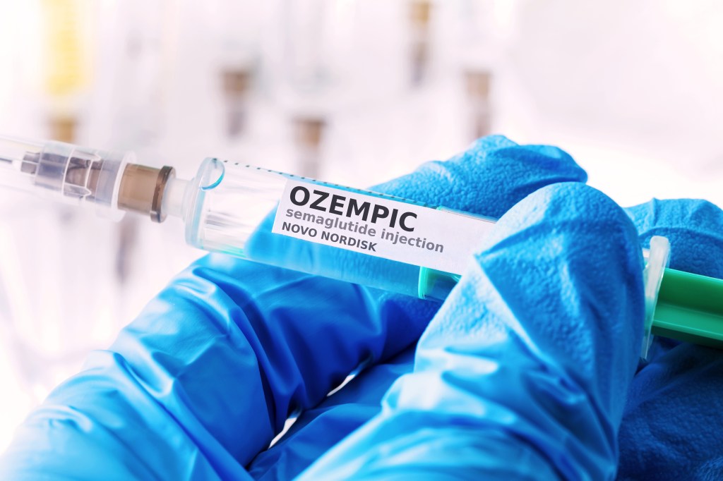Ozempic semaglutide injection in a syringe held with gloved hands.