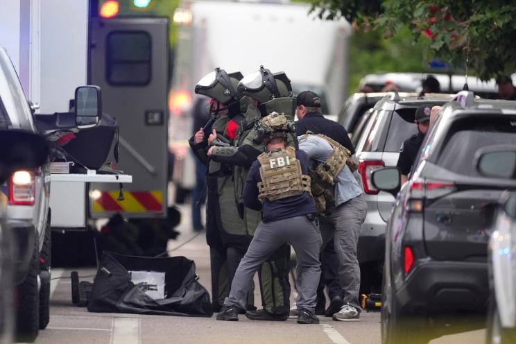 Law enforcement officers in protective gear investigate a scene in Boulder, Colorado.
