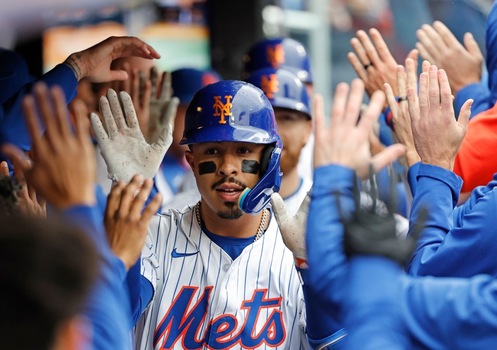 New York Mets baseball player high-fiving teammates in the dugout.