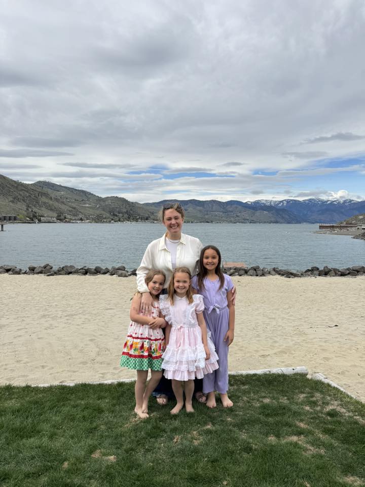 Woman and three young girls on a beach.